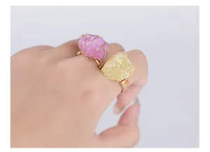 Detalle de anillos hechos a mano con alambre dorado y piedras de cristal moradas y amarillas