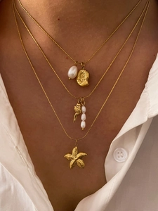 Close-up of layered gold necklace with starfish, seashell, and freshwater pearl charms