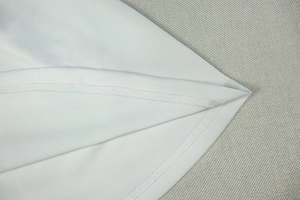 Detailed macro shot showing double-needle stitching and smooth knit fabric of the white dress