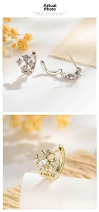Detailed view of fleur-de-lis cross earrings with zircon in silver and gold tones