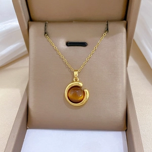 Detail of gold-plated geometric necklace featuring a brown gem inlay and pavé stones