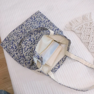 Floral cotton tote bag with white straps on a bed, showing spacious storage capacity