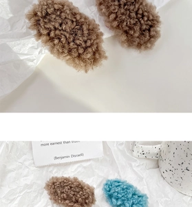Detail of plush lamb wool hair clips in brown and blue with soft fuzzy texture