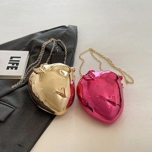 Detail view of heart-shaped acrylic evening bags in reflective gold and rose pink finish