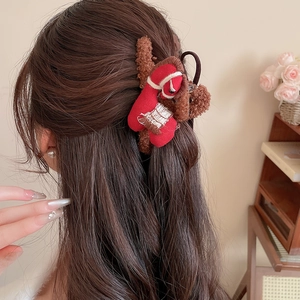 Close-up of a plush fabric horse claw clip in red and brown colors for a winter hairstyle