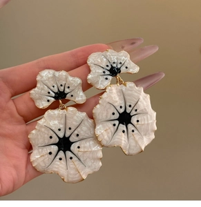 Detailed macro view of large white ginkgo flower earrings with gold edges and black center