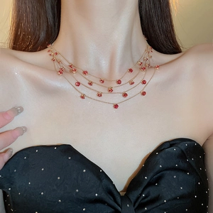 Detail einer mehrlagigen Goldkette mit roten Zirkonia am Hals des Modells gezeigt