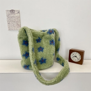 Detailed view of green plush bucket bag featuring blue floral patterns and soft texture
