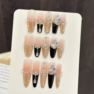 Detail of luxury press-on nails featuring black and pink ombre with rhinestones and pearls