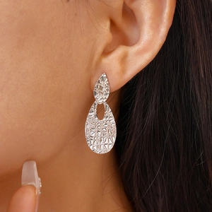 Close-up of silver water-drop earrings with hammered metal texture worn by a model