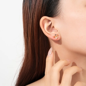 Close-up of elegant gold flower stud earrings with shimmering zircons on model ear