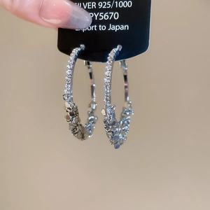 Macro shot of 925 silver hoop earrings with sparkling diamonds on black card holder