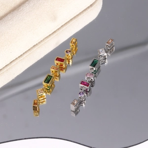 Macro detail of gold and silver earrings with colorful square and round gemstones