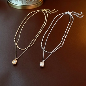 Close-up of double-layered gold and silver necklaces with irregular pearl pendants