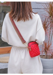 Detail of red quilted nylon crossbody phone bag with multi-color woven wide strap and gold hardware