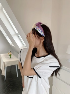 Detail van een paarse gebloemde knoophoofdband gecombineerd met een witte contrastblouse