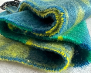 Close-up of soft faux cashmere scarf showing blue-green gradient texture and yellow edges