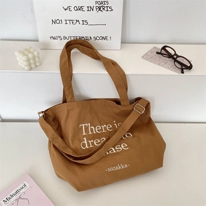 Detail of brown canvas tote with adjustable shoulder strap and dream lettering print