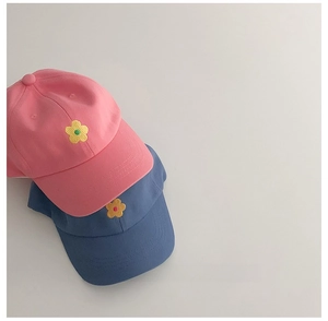 Détail de la broderie fleurie sur les casquettes de baseball en coton rose et bleu