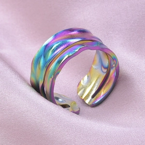 Macro shot of iridescent wave textured stainless steel ring on purple satin fabric