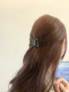 Gros plan d'une petite pince à cheveux en résine vert foncé sur une coiffure