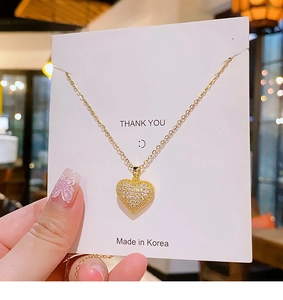 Close-up of a gold heart pendant necklace with shimmering cubic zirconia on a card
