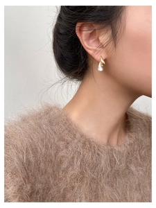 Close-up of elegant gold water drop earrings with white pearl pendants on model