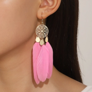 Close-up of bohemian pink feather earrings with golden circular accents on model