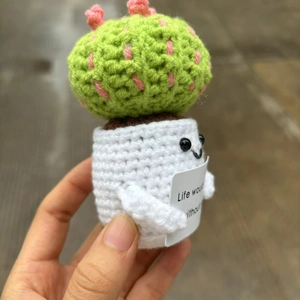 Handmade crochet cactus doll close-up with emotional support sign in a person's hand