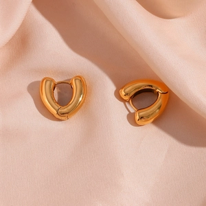 Macro shot of 18K gold heart-shaped hoop earrings on soft pink satin fabric