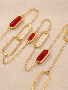 Detail eines roten facettierten Edelstein-Anhängers mit goldenen Hammerschlag-Kettengliedern