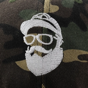 Detailed close-up of high-density white embroidery on a camo cotton baseball cap