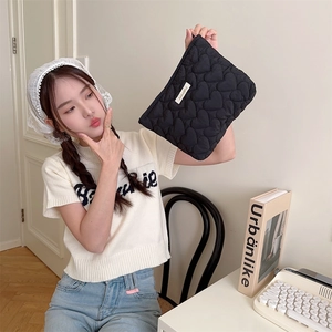 Detailed view of black quilted heart clutch bag with zipper closure and SaLa label