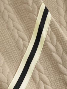 Close-up of khaki quilted fabric with striped webbing detail on a men's hoodie