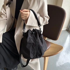 Détail du sac seau en nylon noir avec cordon de serrage porté par un mannequin en intérieur