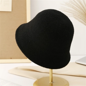 Classic black wool felt bucket hat displayed on a gold metal stand in a cozy setting