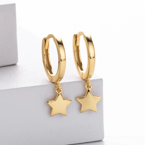 Close-up of gold s925 silver star pendant hoop earring on a white geometric surface