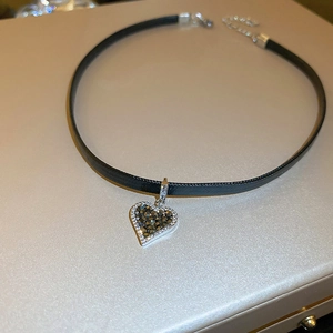 Close-up of heart pendant with dark crystals and sparkling rhinestones on black choker