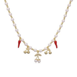Detail of red chili and gold cherry pendants on a pearl beaded necklace chain