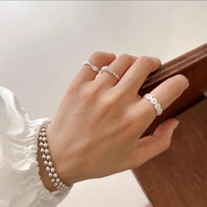 Detail of 925 sterling silver daisy ring set with beaded bracelets on female hand
