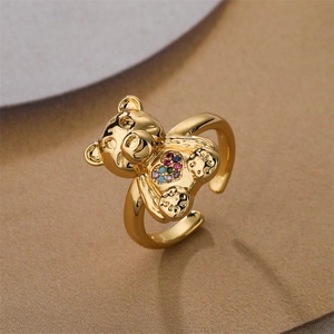 Close-up of golden bear ring with a colorful heart-shaped zircon on warm background