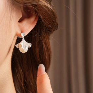 Gros plan d'un mannequin portant des boucles d'oreilles ginkgo en argent, perle et zircon