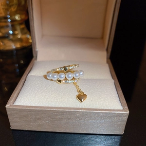 Close-up of gold-plated multi-layer ring with pearls, zircons, and a heart charm