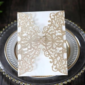 Detail of laser-cut glitter wedding invitation with elegant floral lace pattern