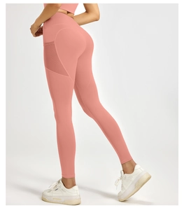 Detail view of coral pink high-waisted yoga pants with mesh side pockets on the thigh