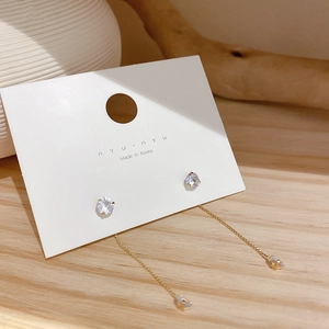 Detalle macro de elegantes pendientes largos con borlas y pedrería en tarjeta de joyería