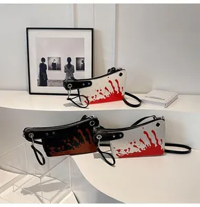 Detail of unique cleaver-shaped crossbody bags with red artistic splatter and metal eyelets