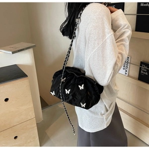 Detail of black pleated cloud bag with silver chain strap and white 3D butterfly charms