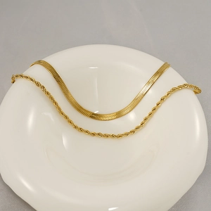Layered gold snake chain and twisted rope necklace set displayed on a white tray