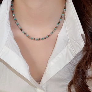 Close-up of beaded flower pendant necklace in green and brown tones on female neck